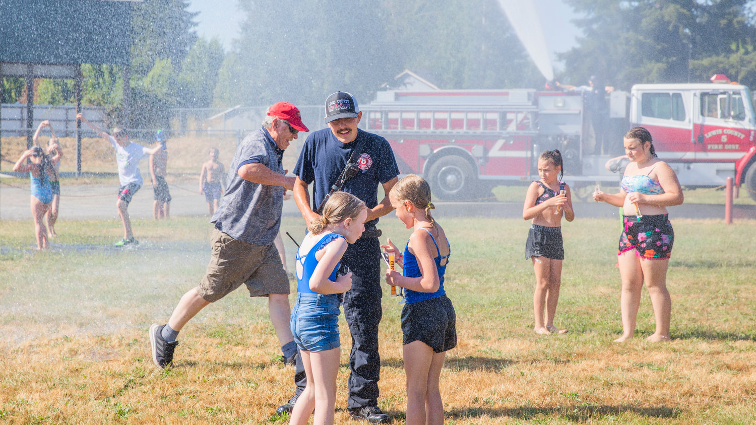 Lewis County Fire District 5 firefighters pass out freeze pops as visitors cool off Friday in Napavine.